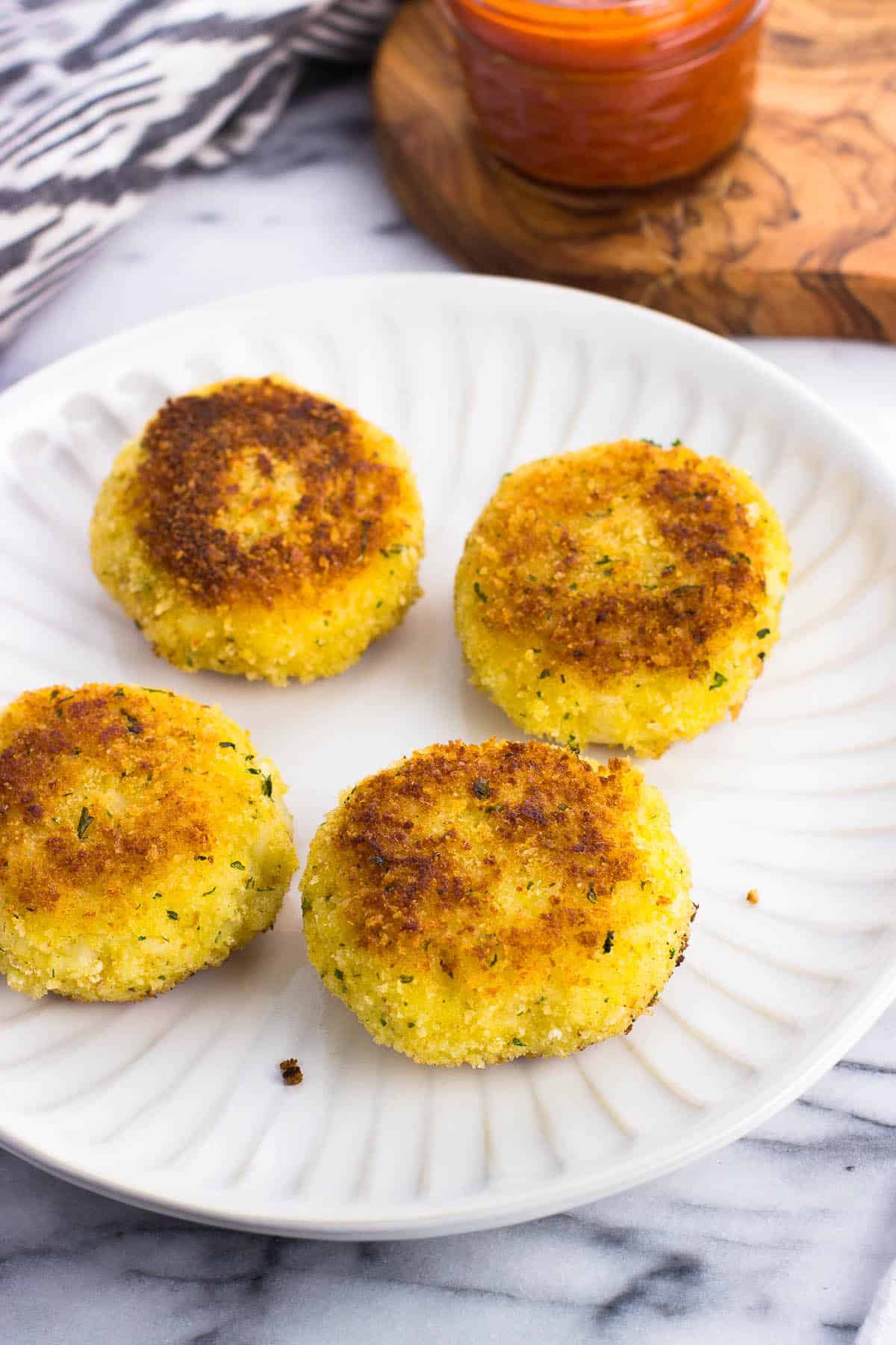 Four risotto cakes on a plate.