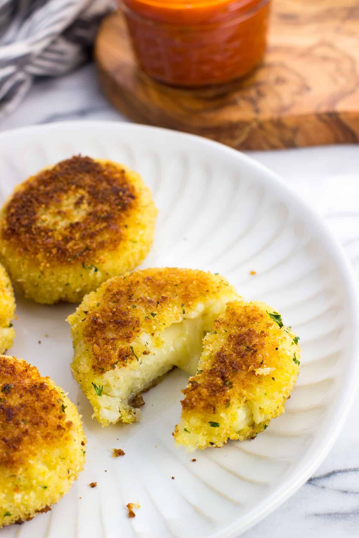 Risotto cakes on a plate with the front cake cut in half.