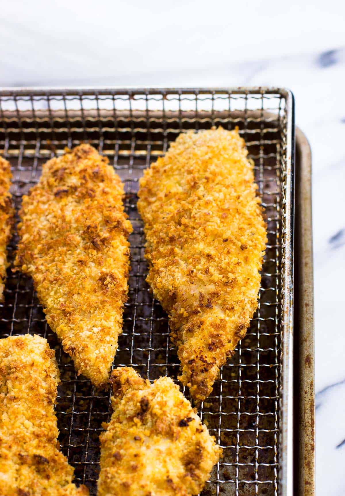 Air fryer chicken tenders on a metal air fryer basket.