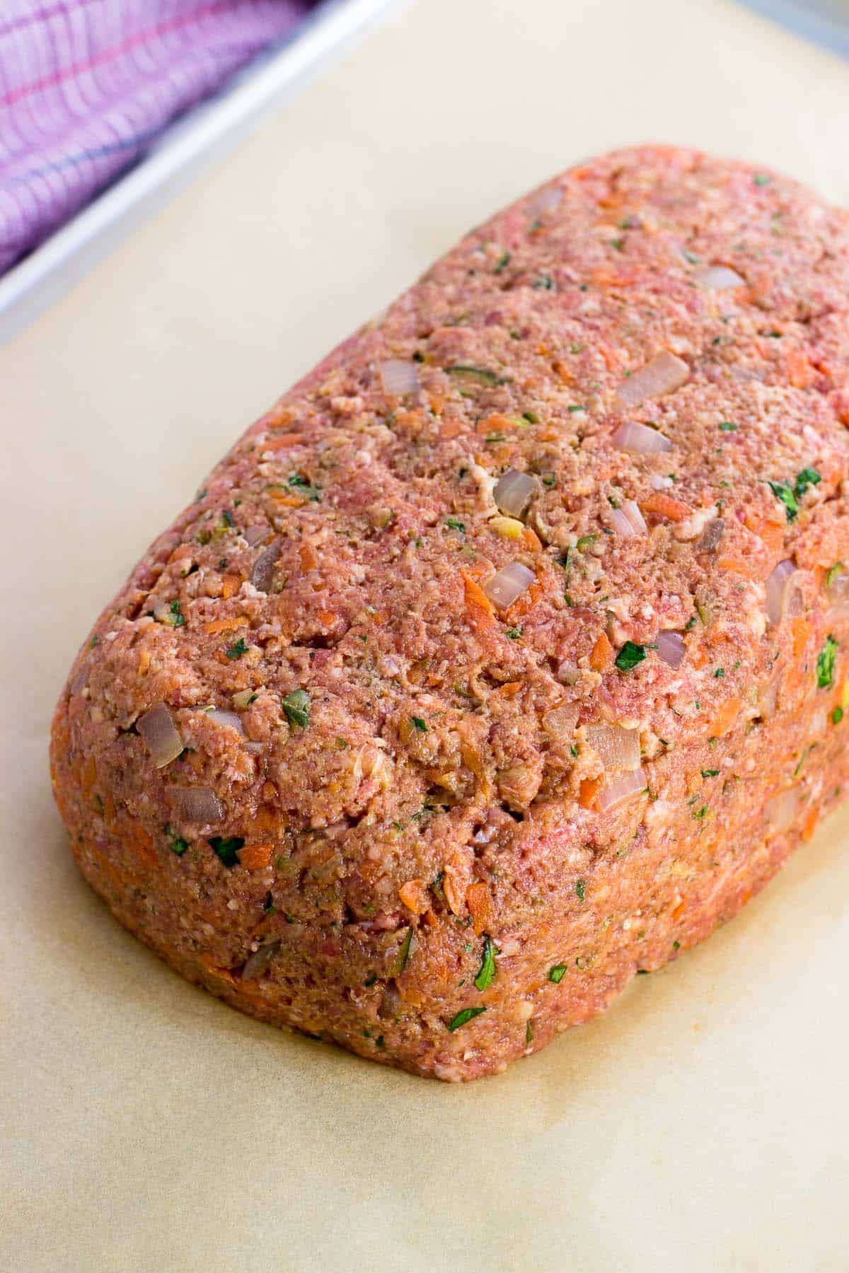 A shaped meatloaf on a parchment-lined sheet pan.
