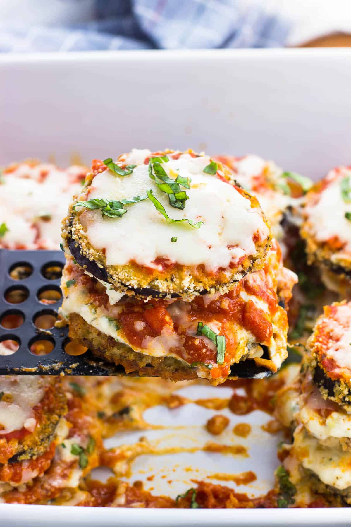 A spatula lifting out an eggplant stack from the dish.