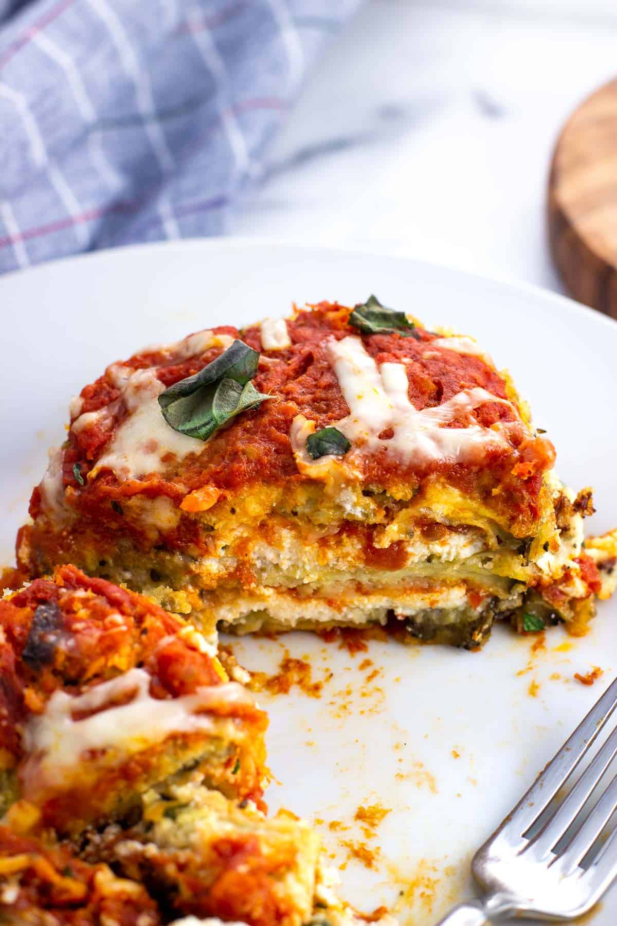 An eggplant stack on a plate cut in half to show the layers.