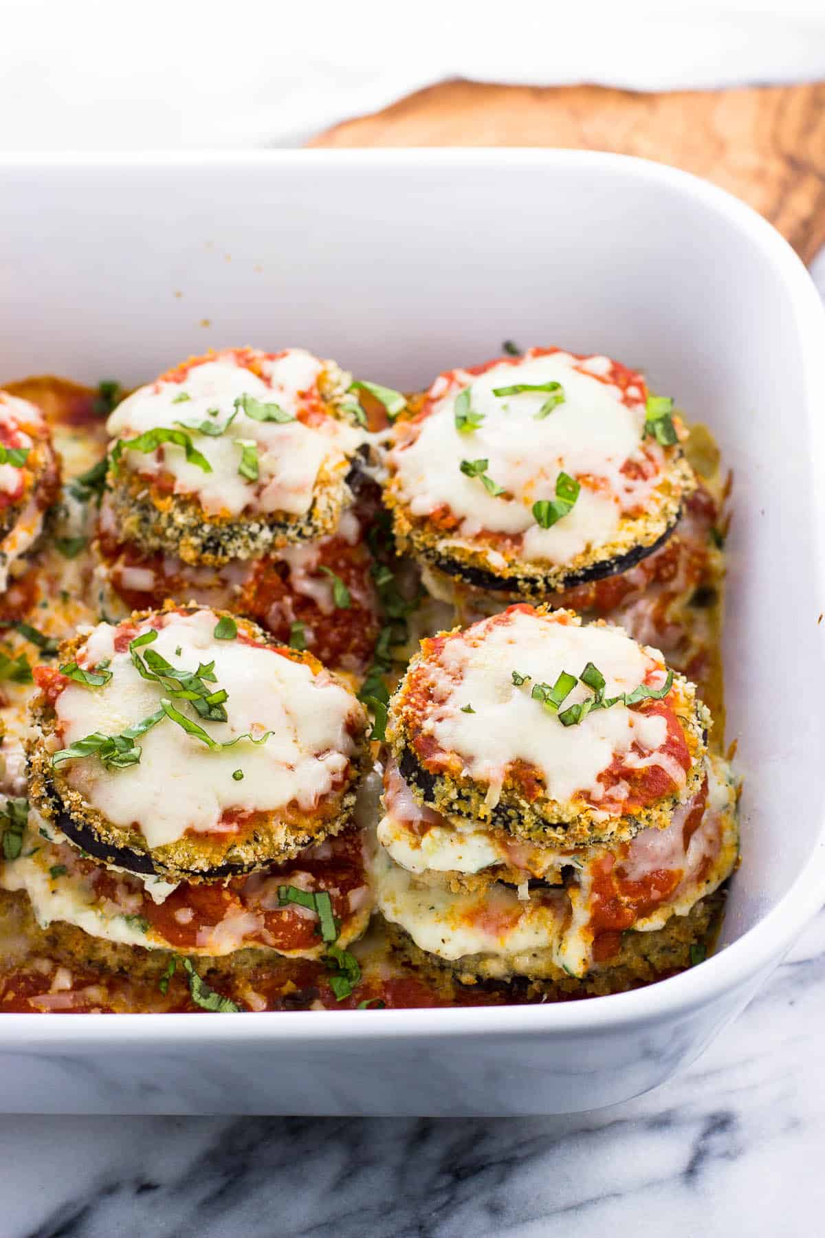 Basil-garnished eggplant stacks in a large baking dish.