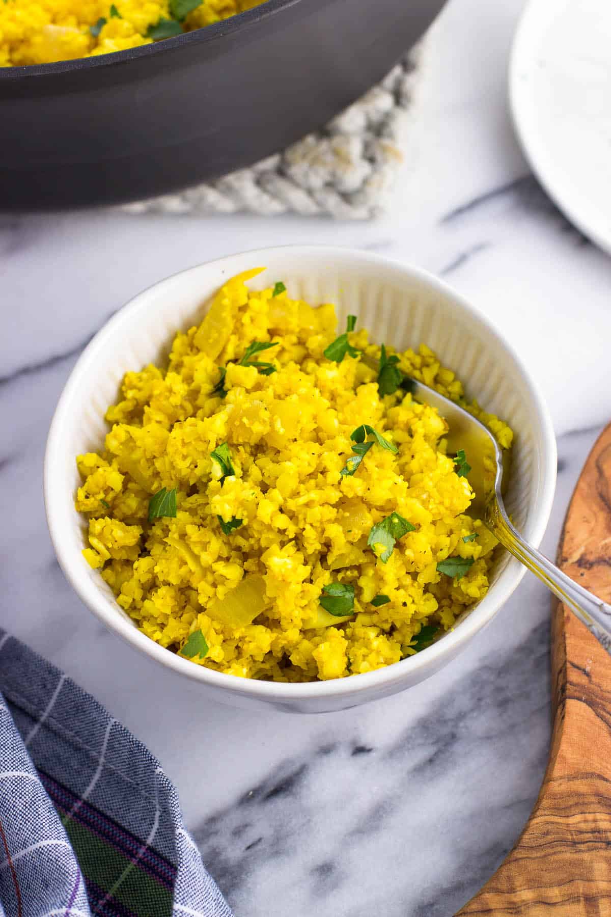 A small bowl of turmeric cauliflower rice with a fork.