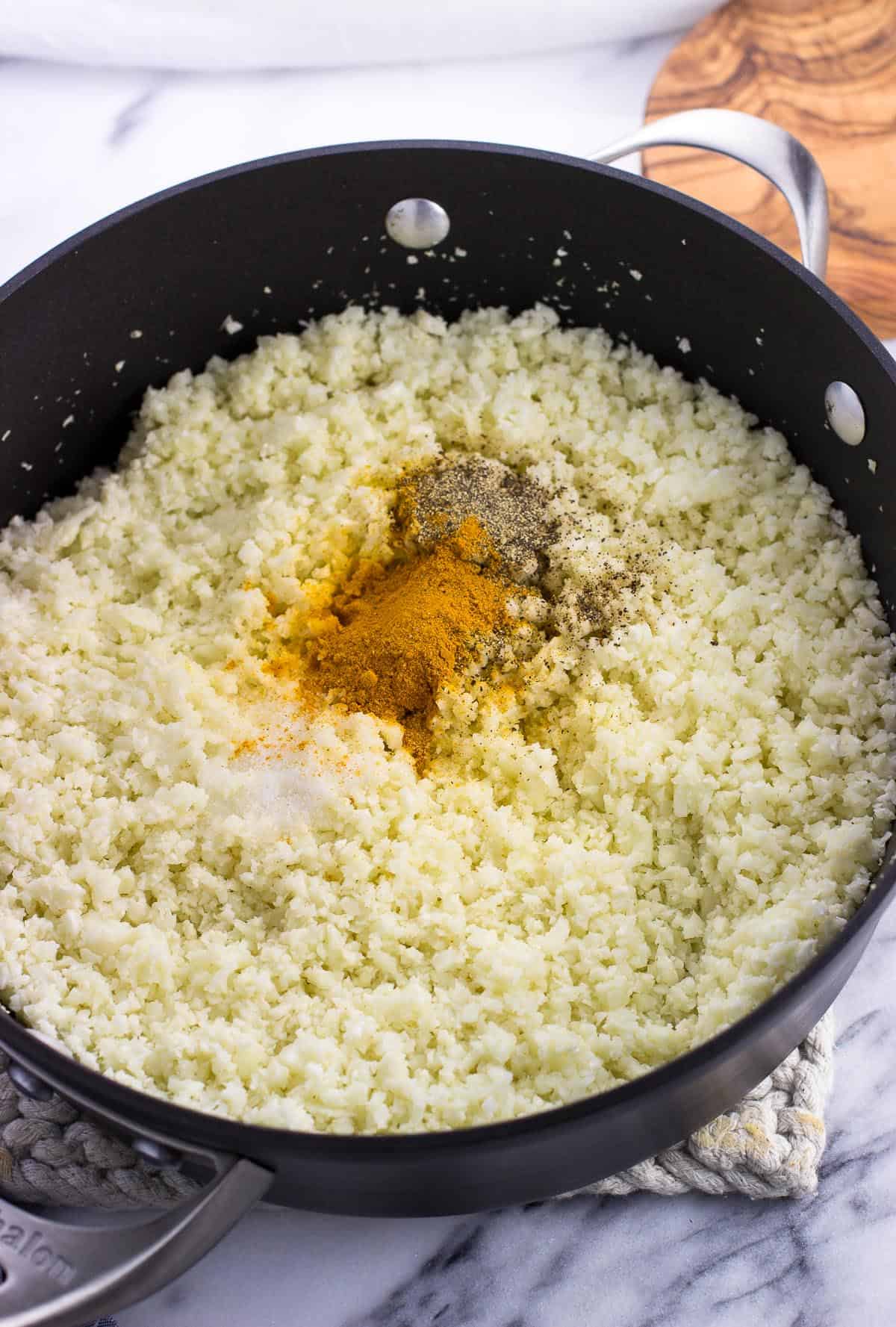 Riced cauliflower and spices in a large pan.