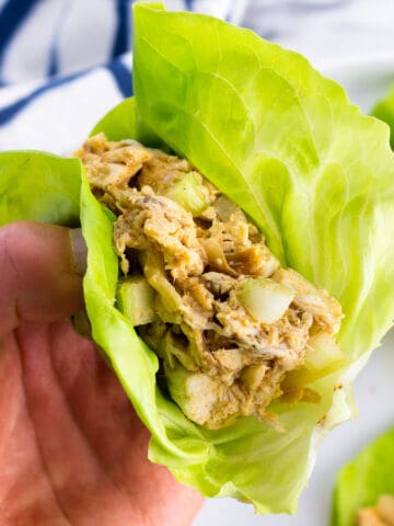 A hand holding a chicken salad lettuce wrap.