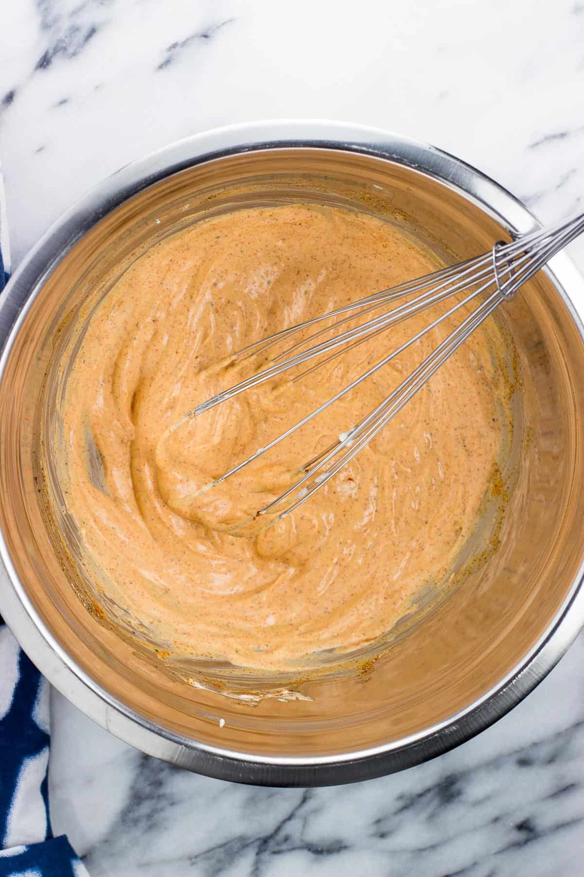 Smoky chicken salad sauce in a metal mixing bowl with a whisk.
