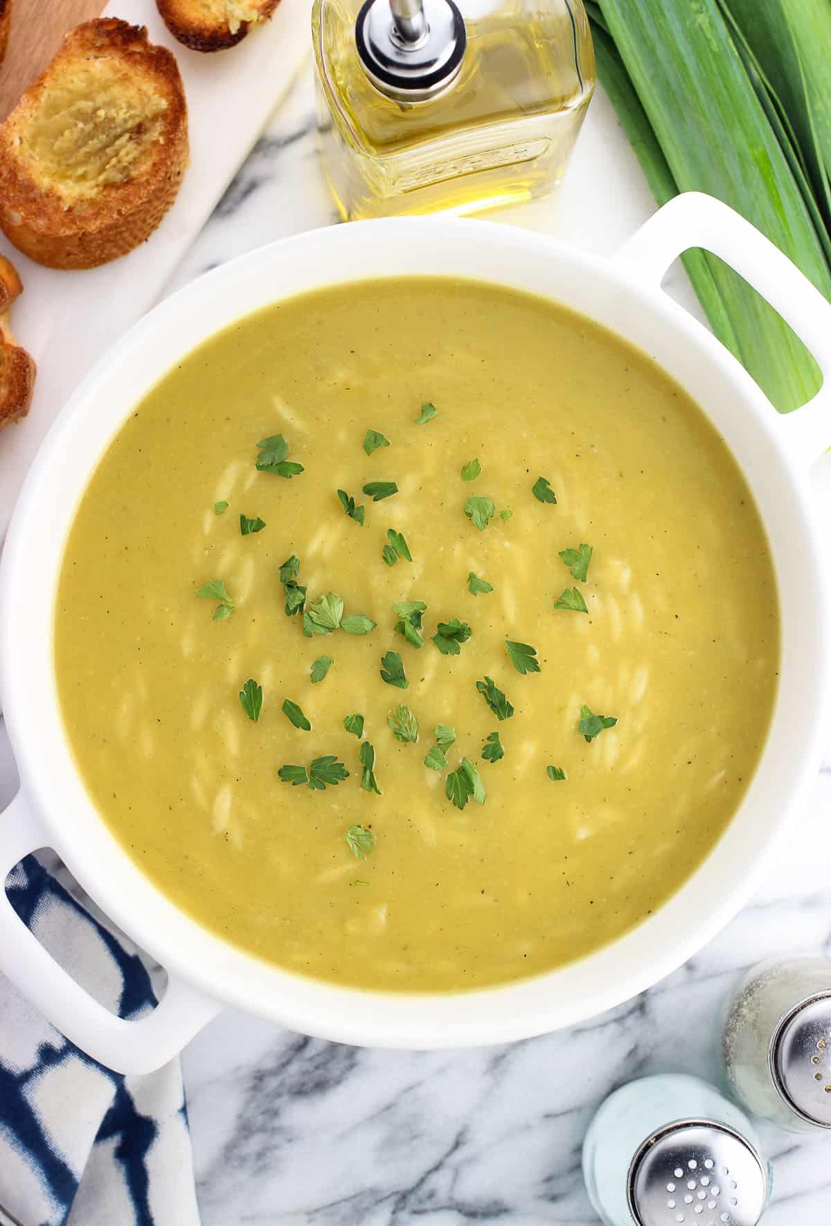 A large ceramic pot of soup next to a tray of crostini.