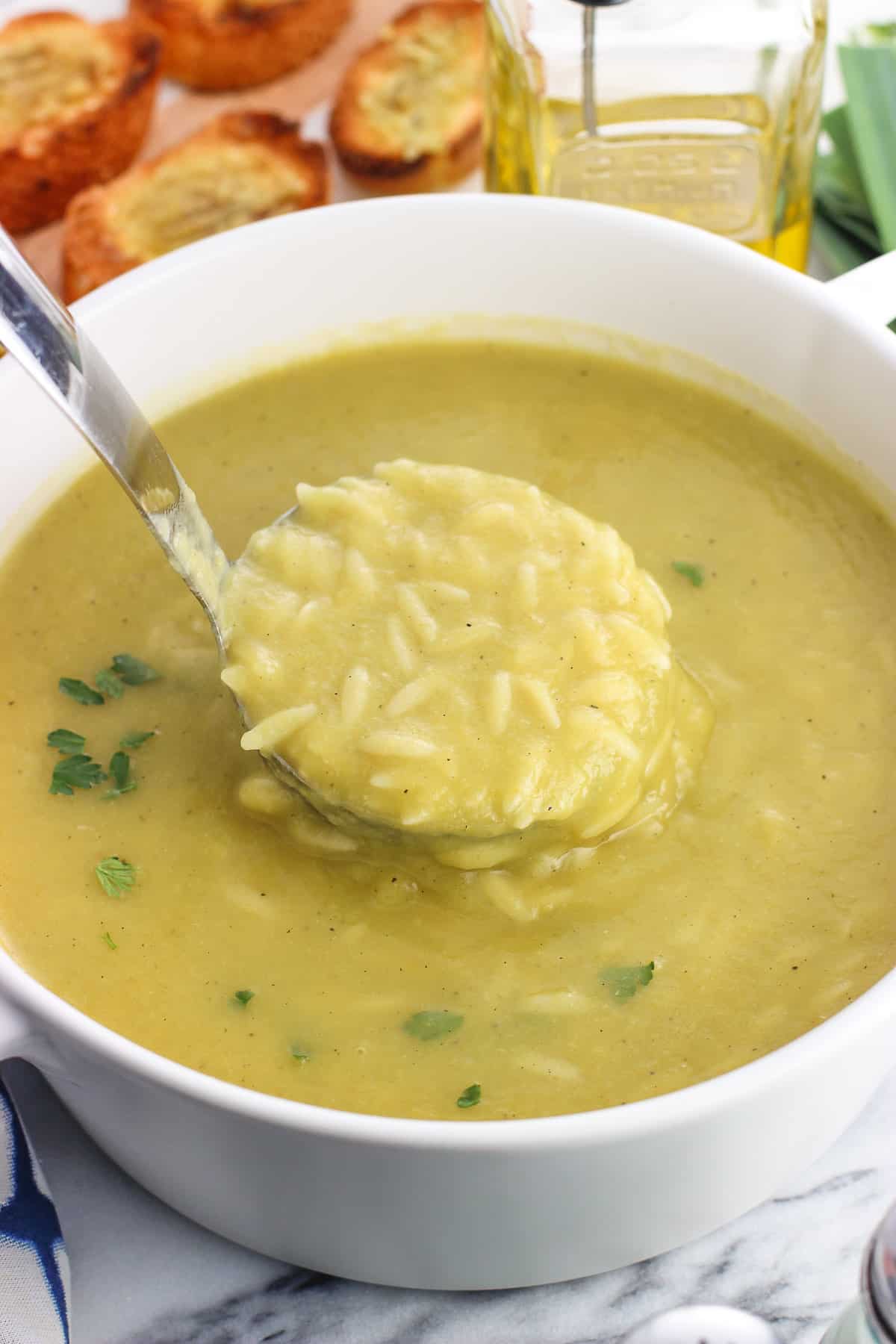 A ladle of potato leek soup lifted out of the pot.