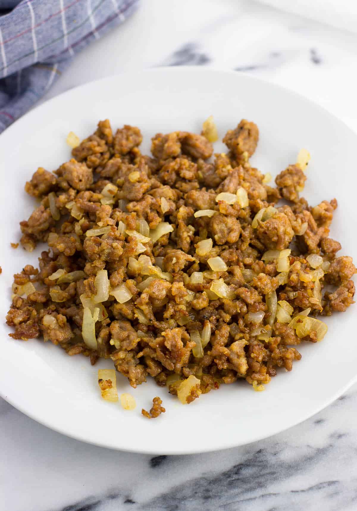 Cooked and crumbled sausage and onion on a plate.