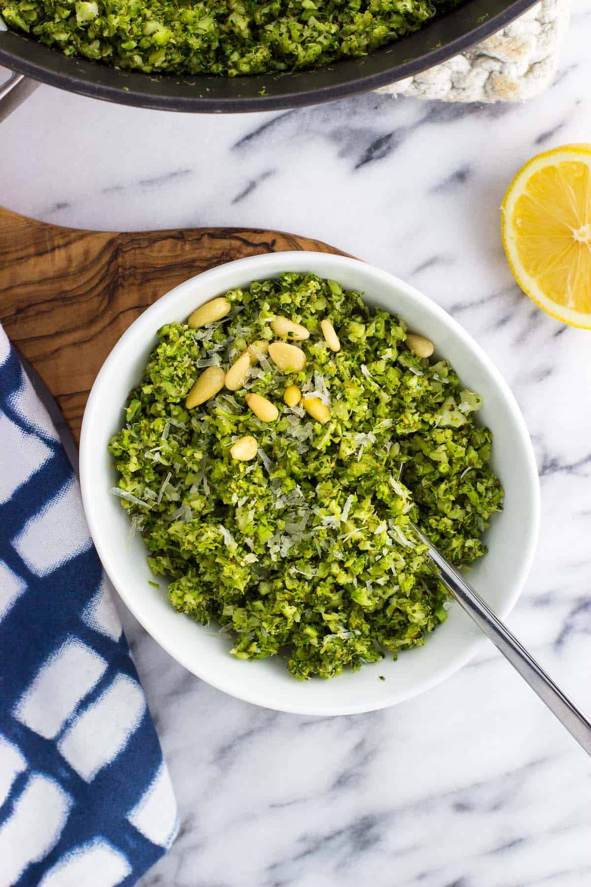 A bowl of pesto broccoli rice topped with pine nuts.