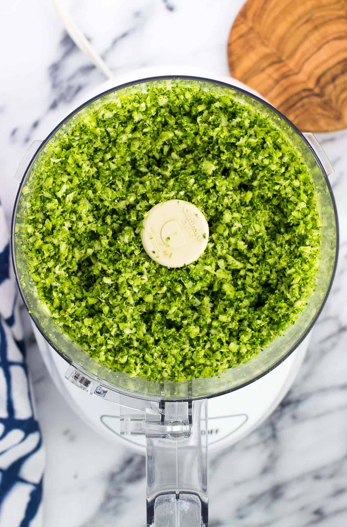 Riced broccoli in the bowl of a food processor.