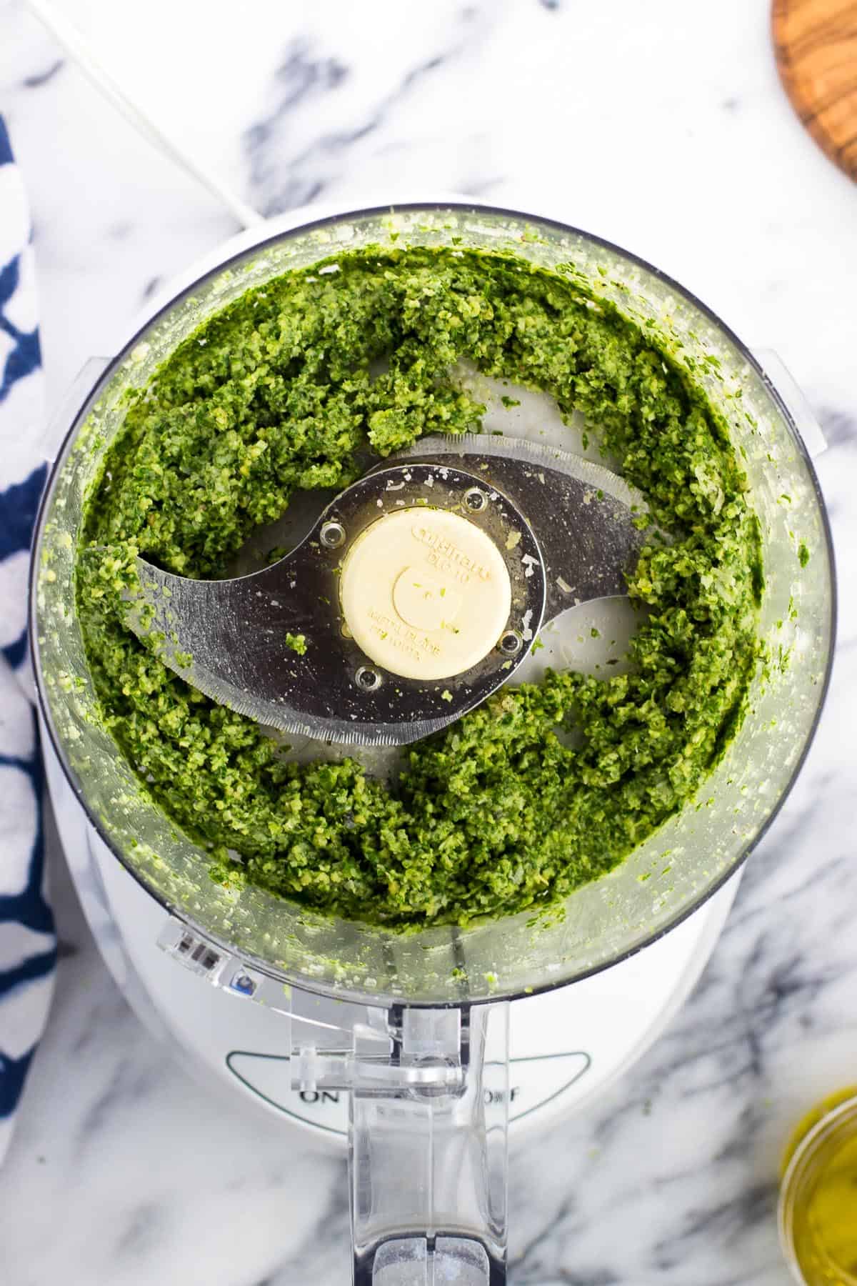 Finely chopped basil and pesto ingredients in the food processor.