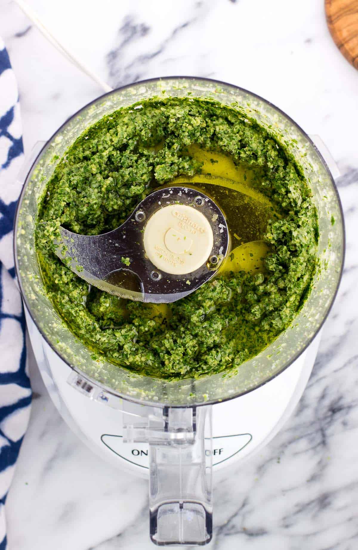 Olive oil poured into the food processor with the pesto ingredients.