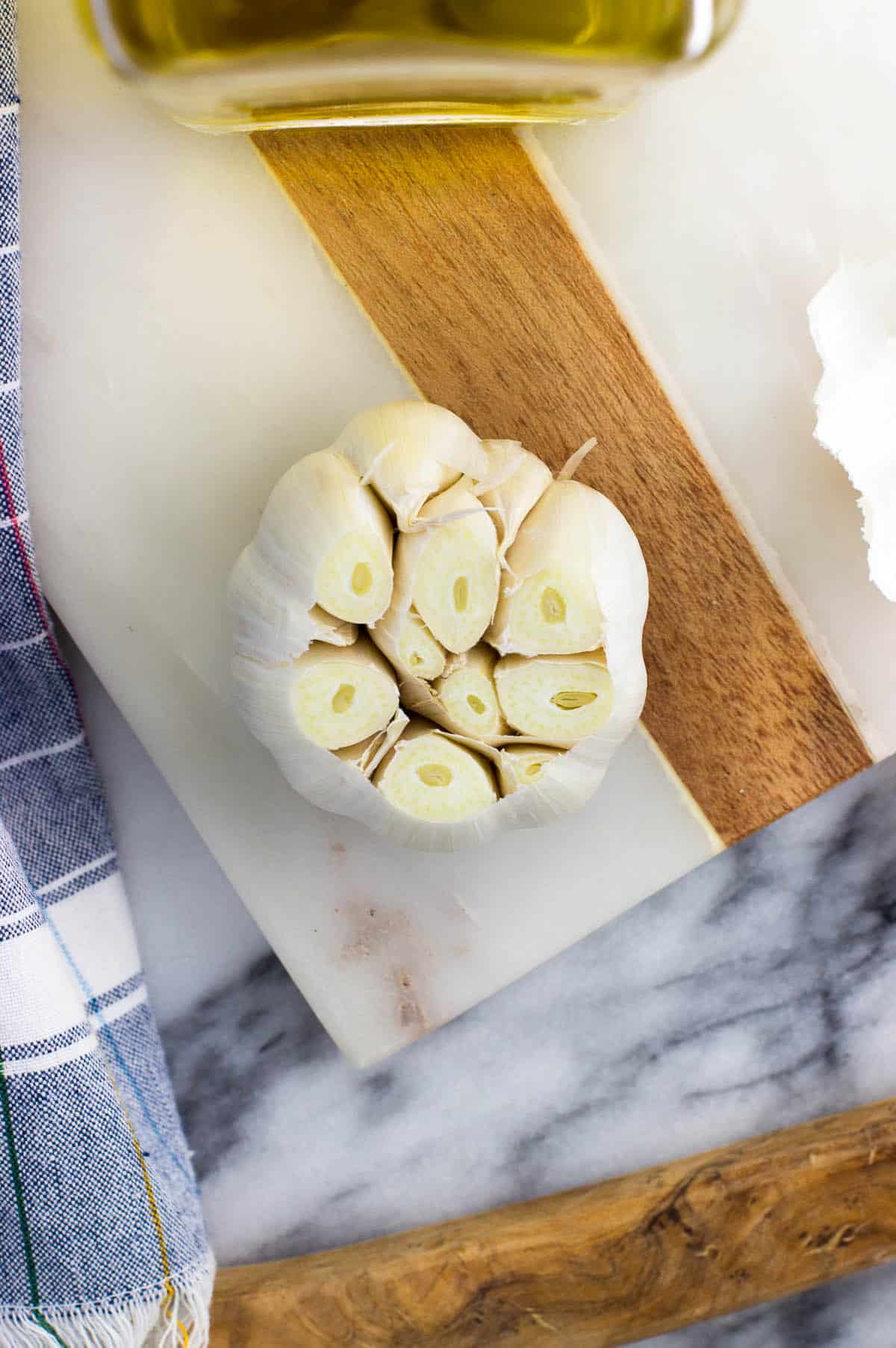 A head of garlic with the very top sliced off to expose the cloves.