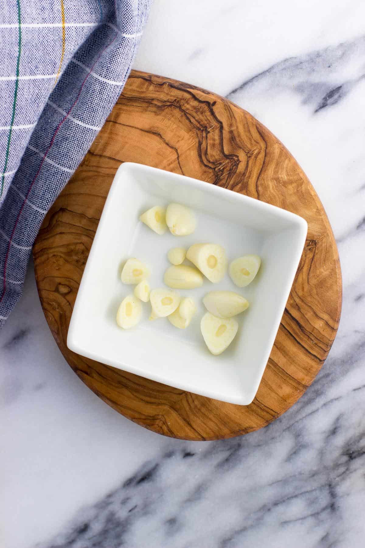 Sliced off ends of garlic heads in a small bowl.