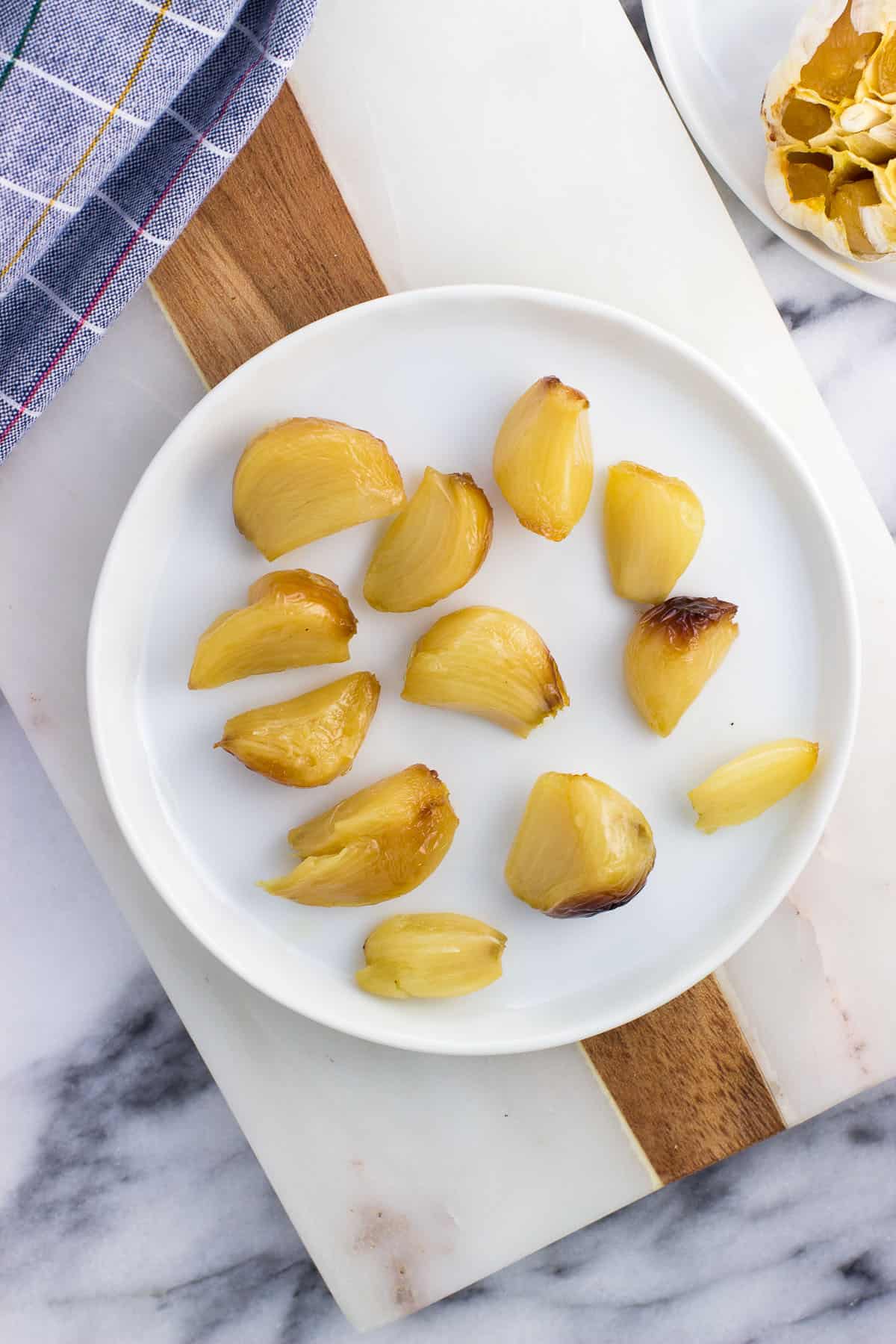 Twelve roasted garlic cloves on a plate.