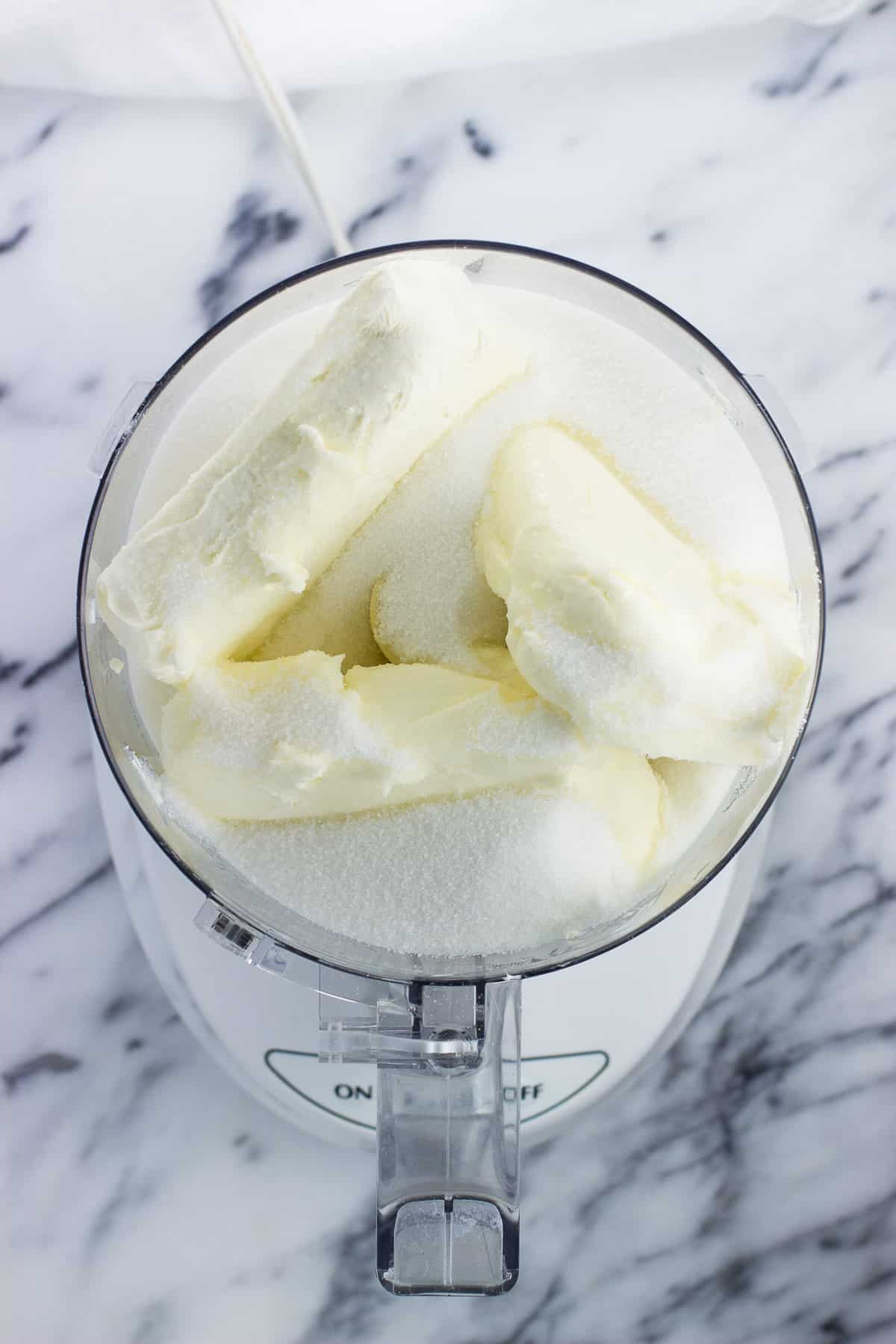 Cream cheese blocks and sugar in the food processor.