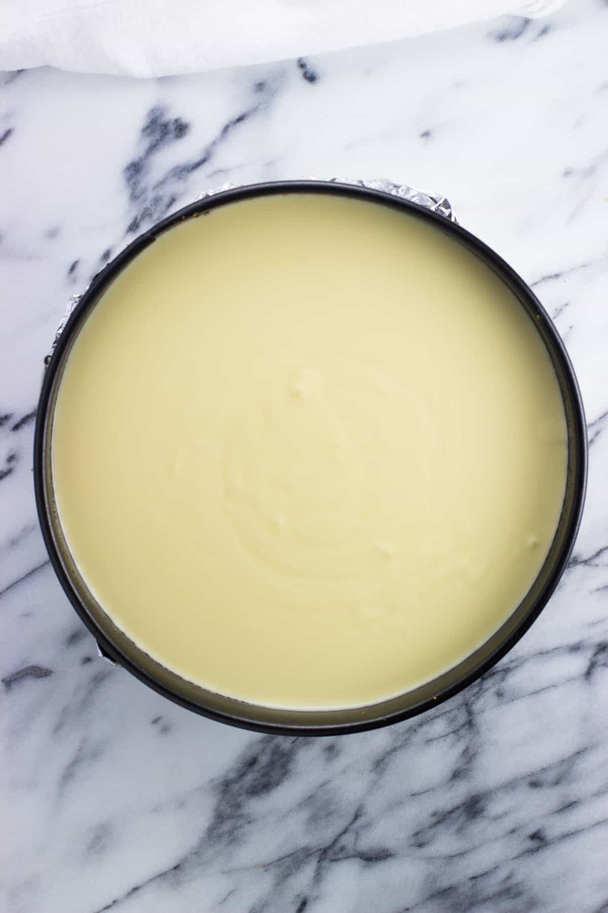 Cheesecake batter poured into a springform pan before baking.