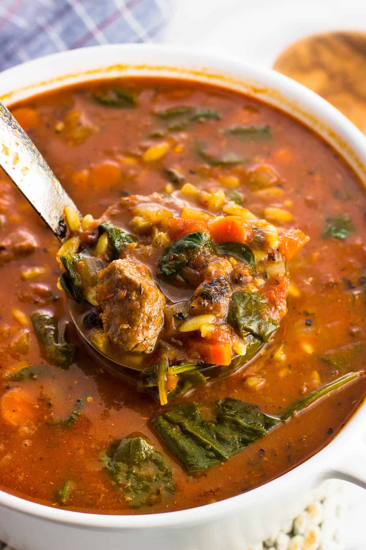 A ladle lifting out a big scoop of soup from a pot.