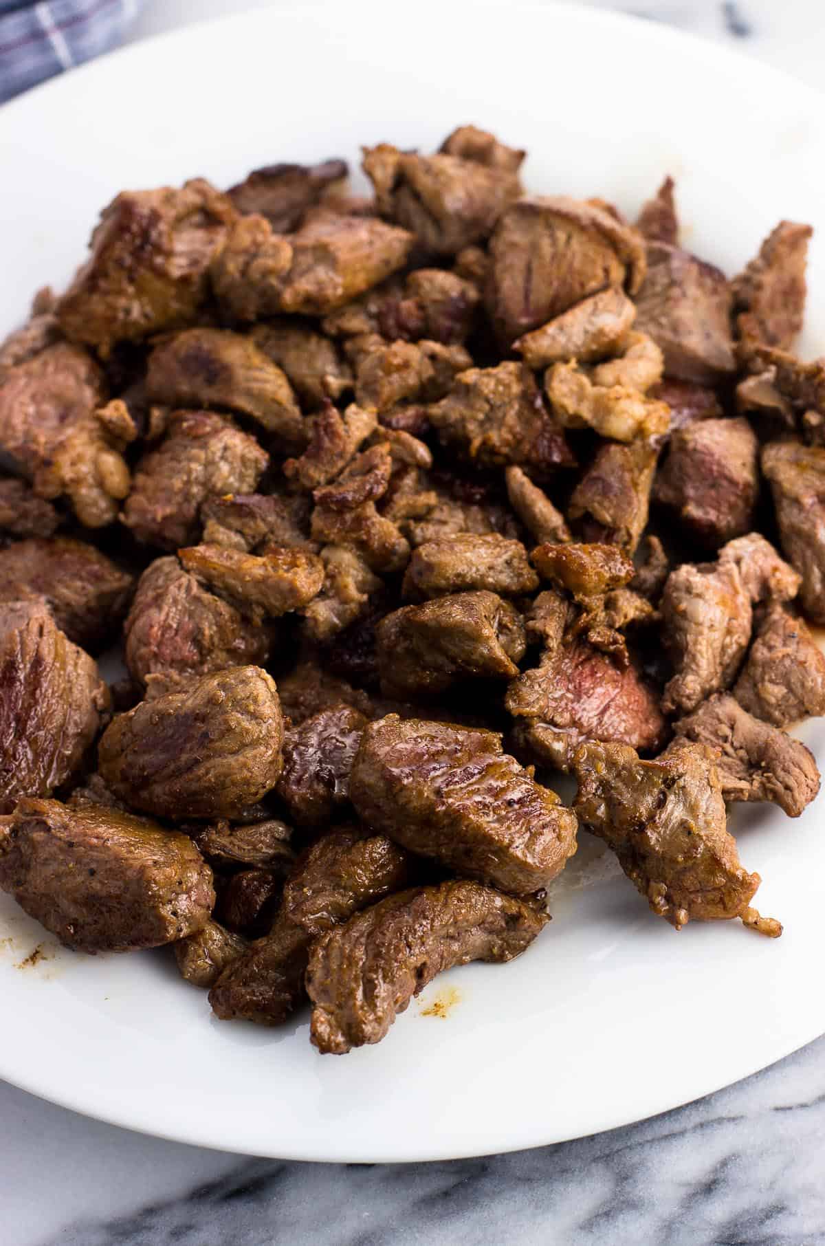 Browned stew meat pieces on a plate.