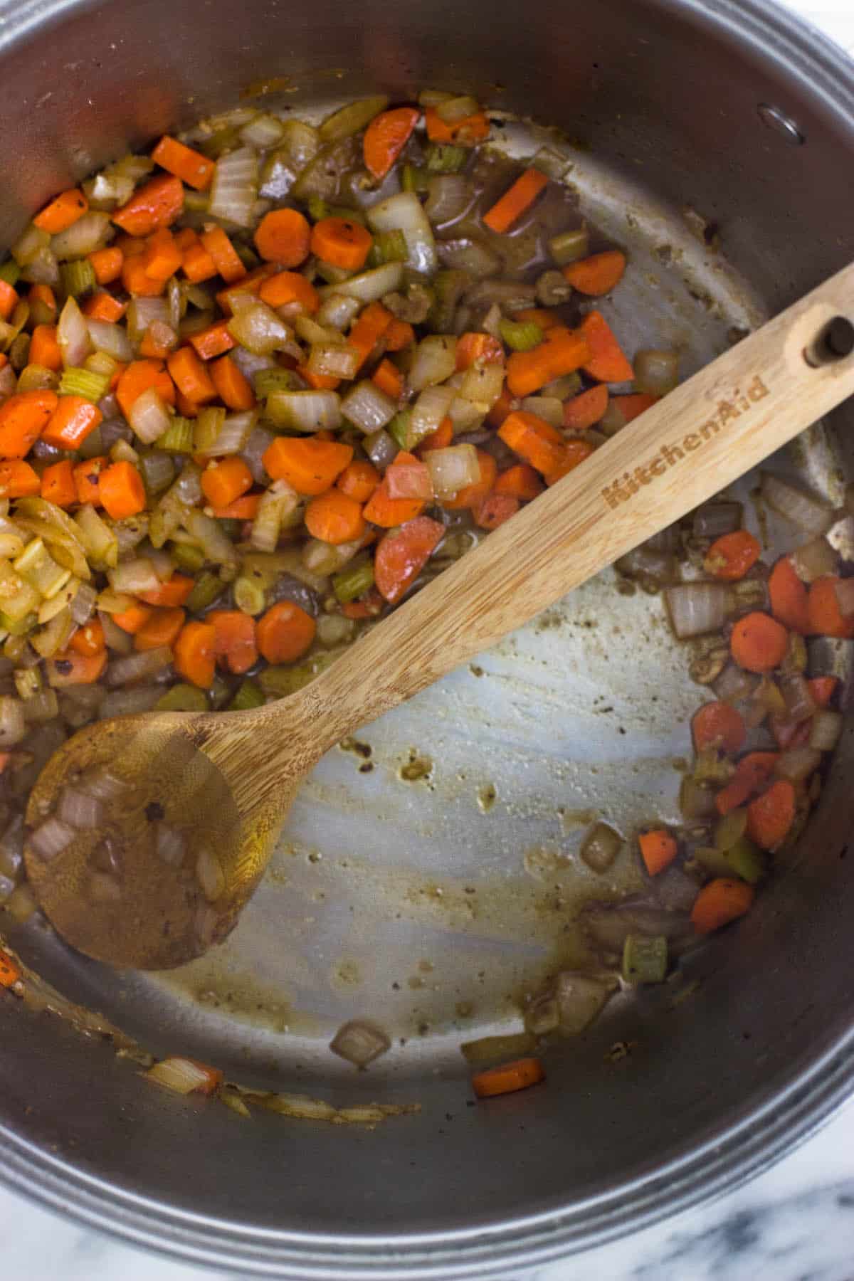 A wooden spoon in the pot showing the scraped up fond.