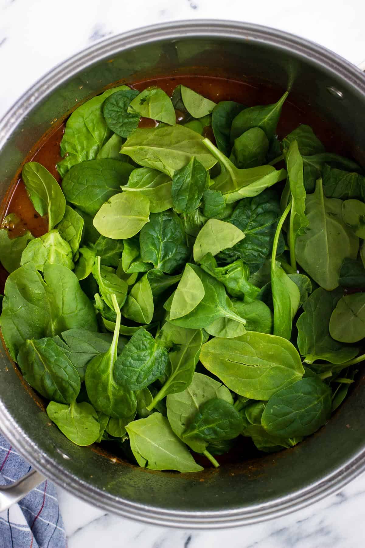 Spinach added to the pot of soup.