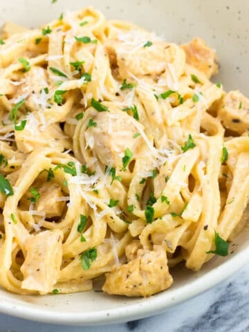 A plate of buffalo chicken alfredo pasta garnished with parsley.