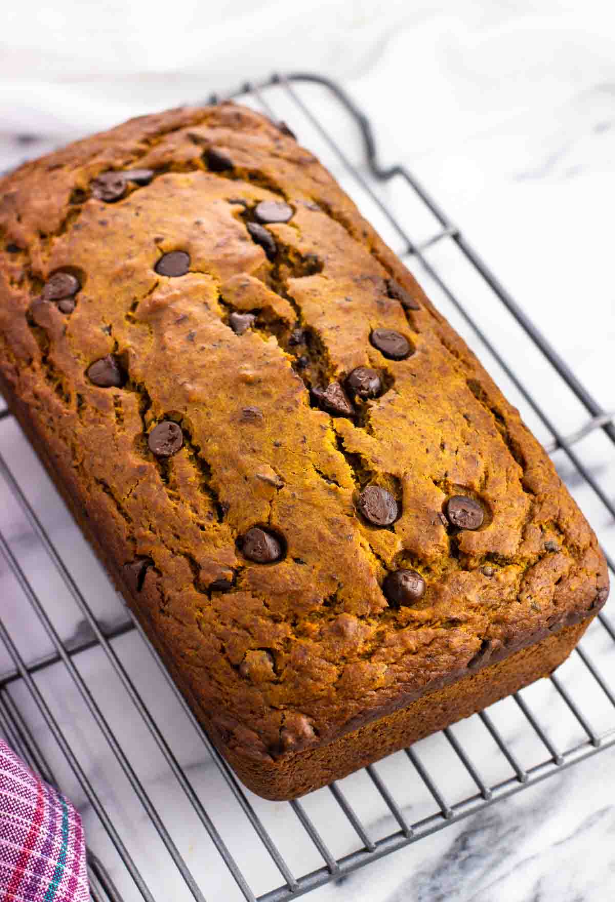 A whole loaf of bread on a wire cooling rack.