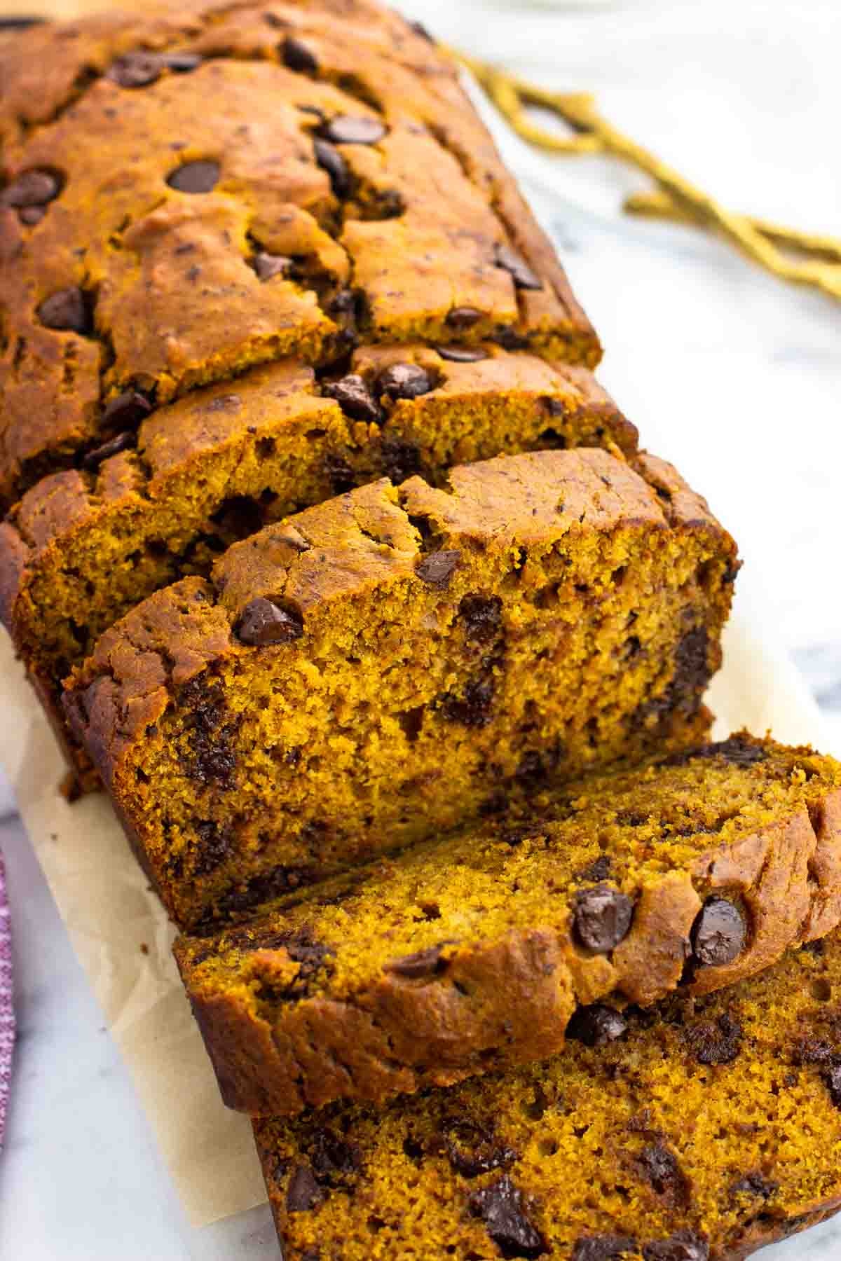 A loaf of pumpkin banana bread half cut into slices.