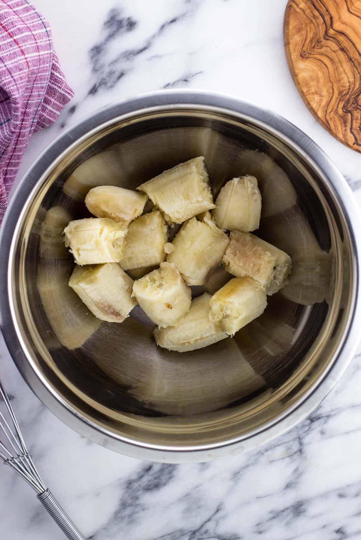 Overripe bananas cut into pieces in a mixing bowl.