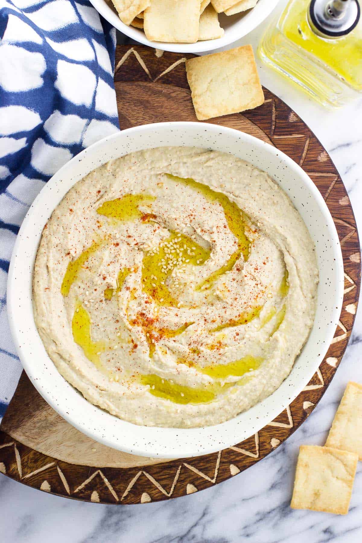 A bowl of roasted garlic hummus next to a bowl of pita chips.