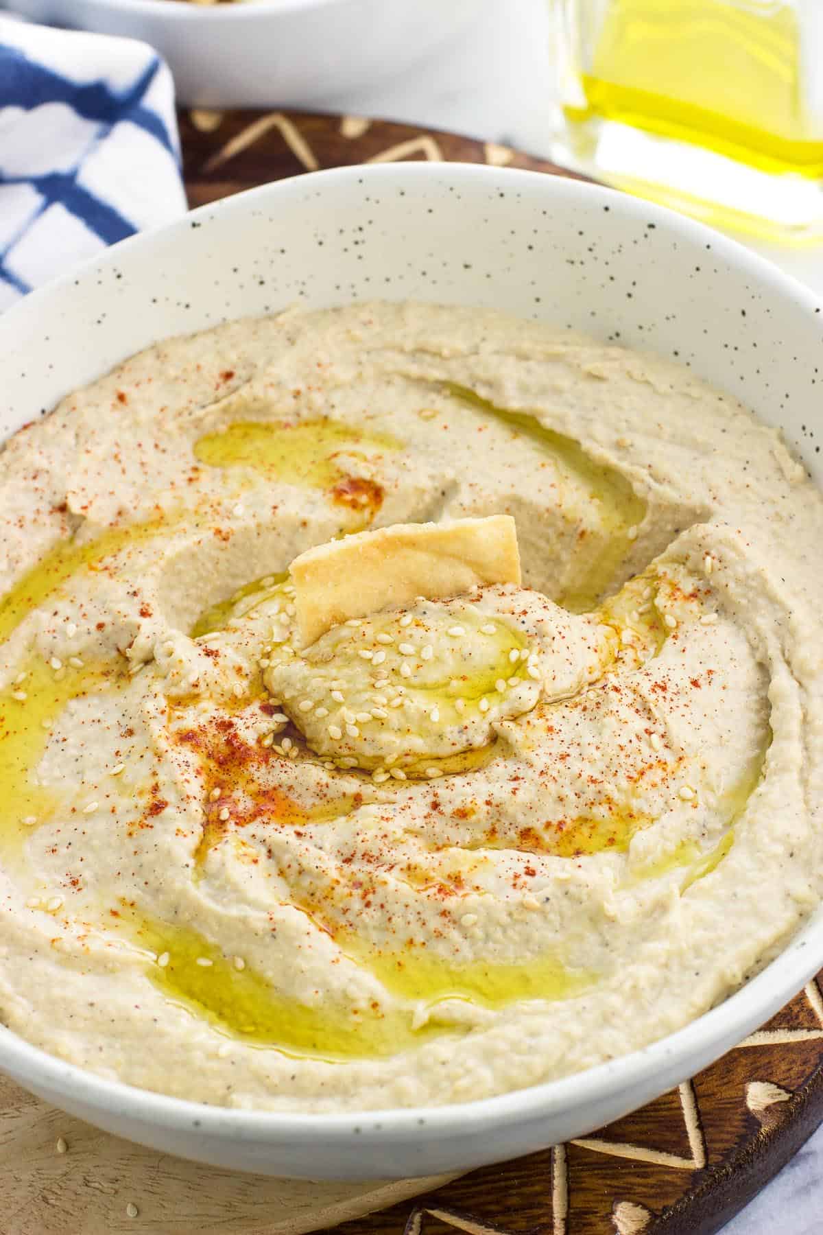 A pita chip scooped into a bowl of hummus.