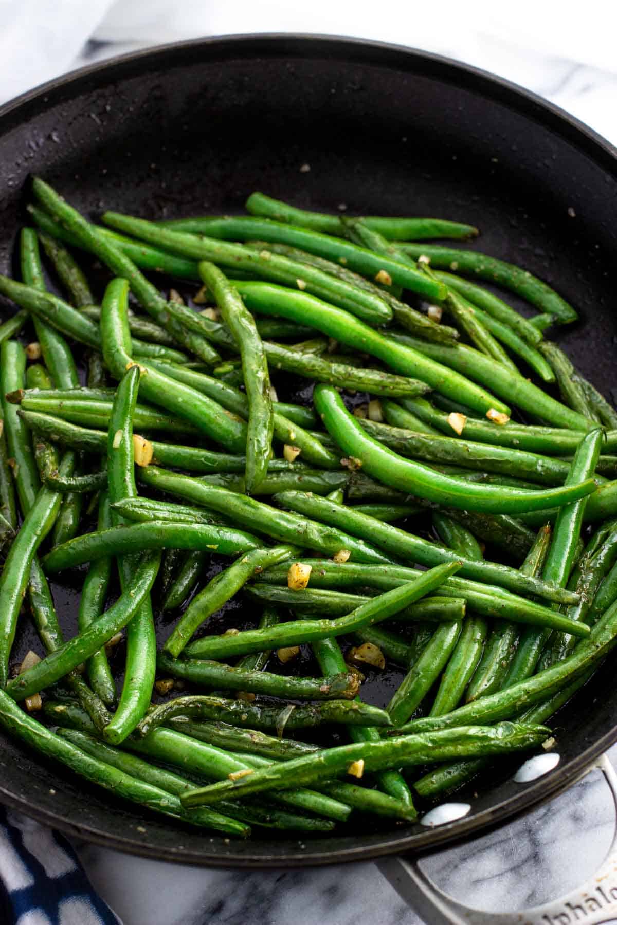 Fully sauteed green beans and garlic in a pan.