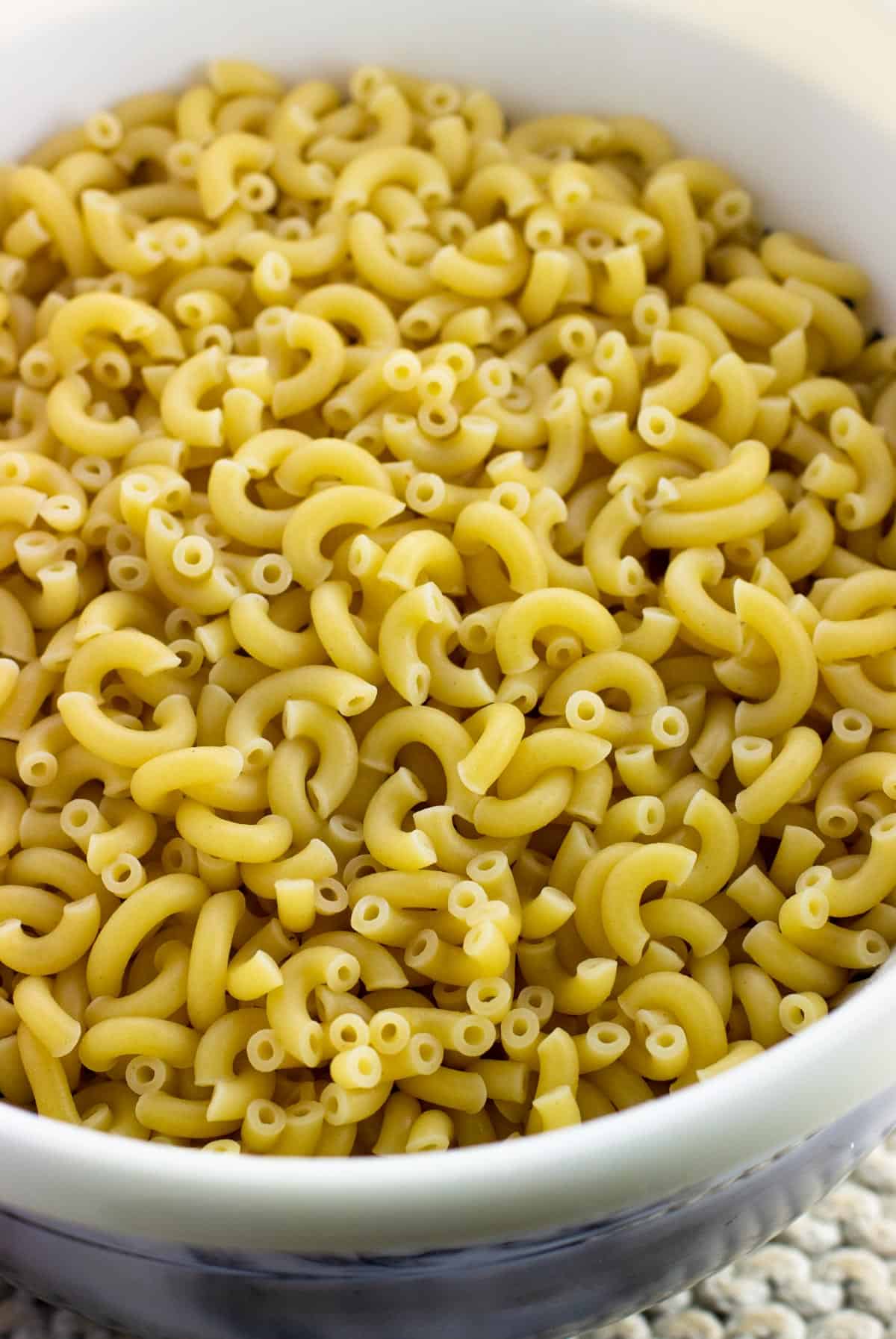 Cooked elbow macaroni in a large strainer.