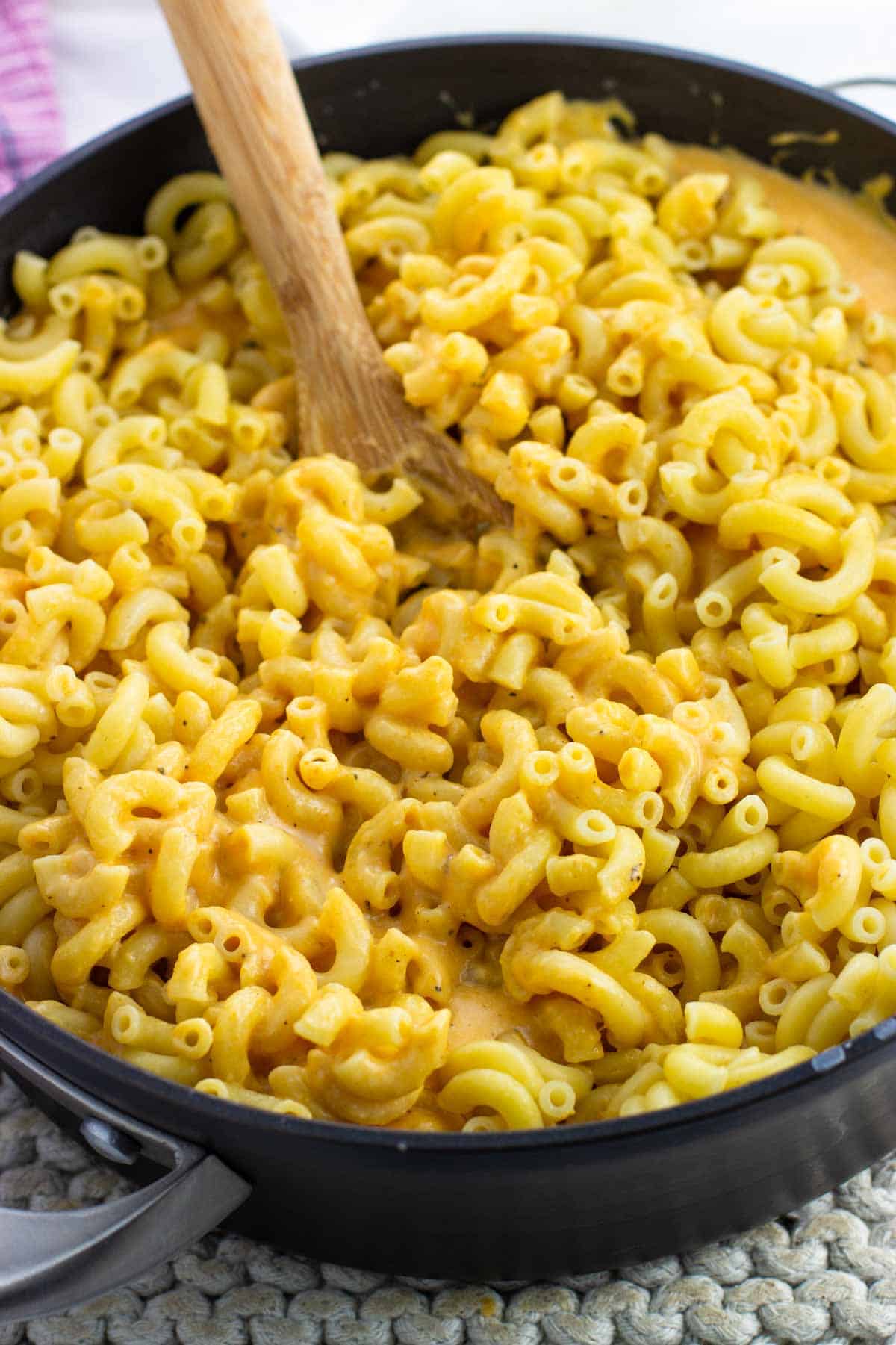 Cooked macaroni being stirred into the pumpkin cheese sauce.
