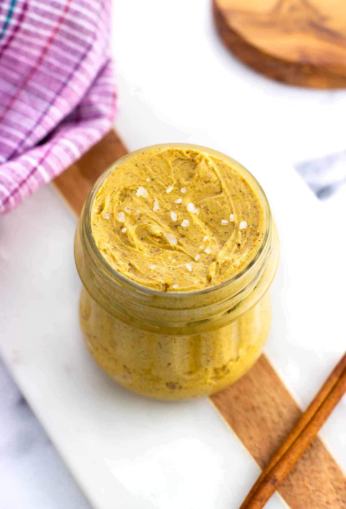 A jar of pumpkin compound butter topped with flaky salt.