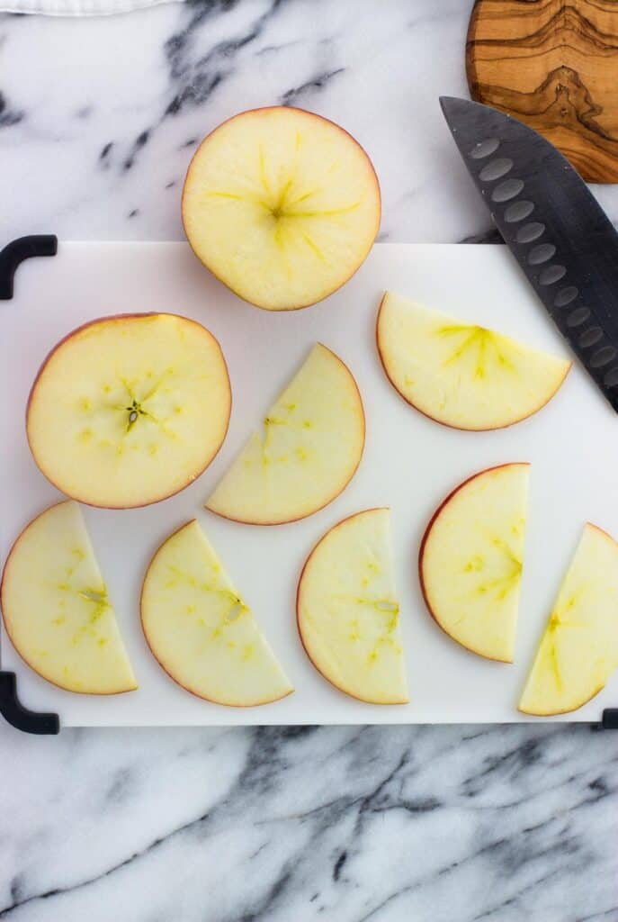 Thin, horizontally sliced apple slices on a cutting board.