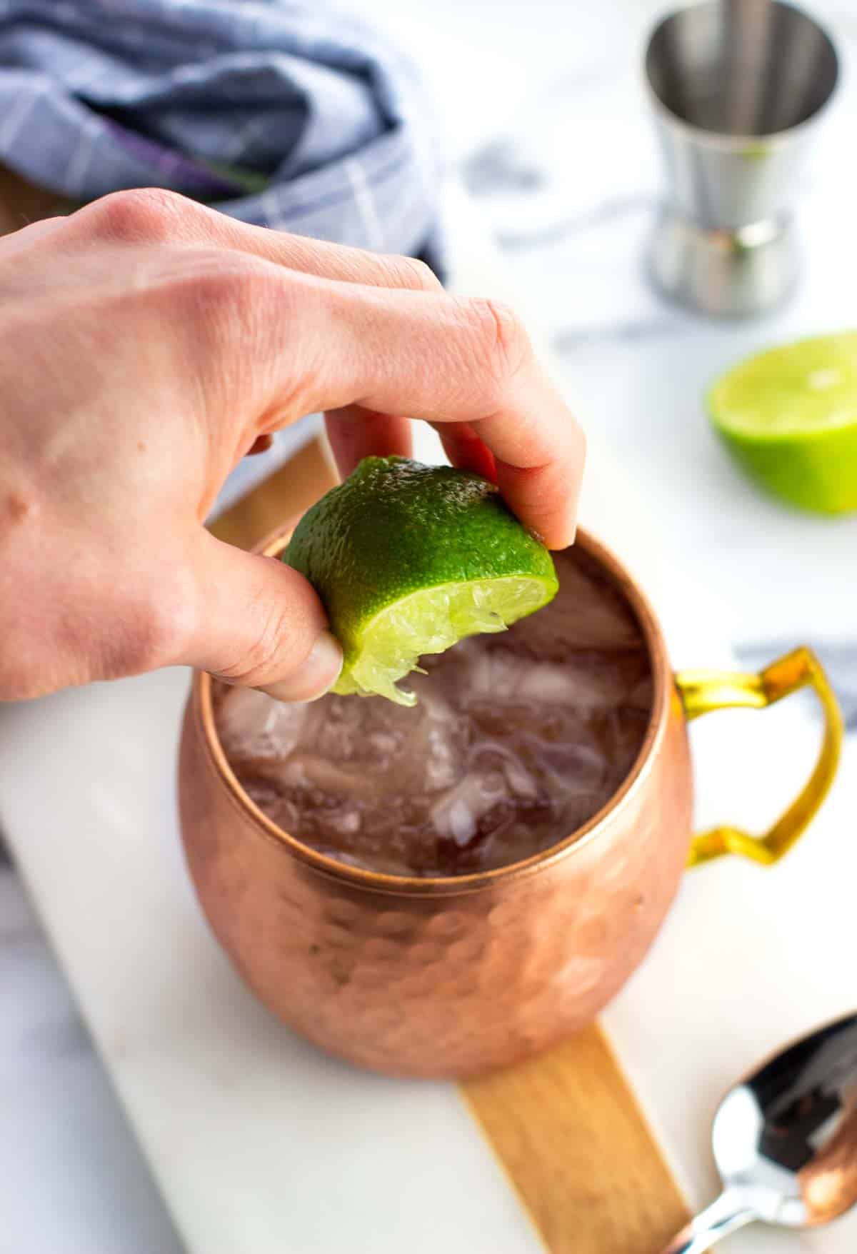 A lime half being squeezed into a Moscow mule.