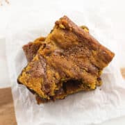 Two pumpkin brownies stacked on top of one another with a bite taken out of the top one.