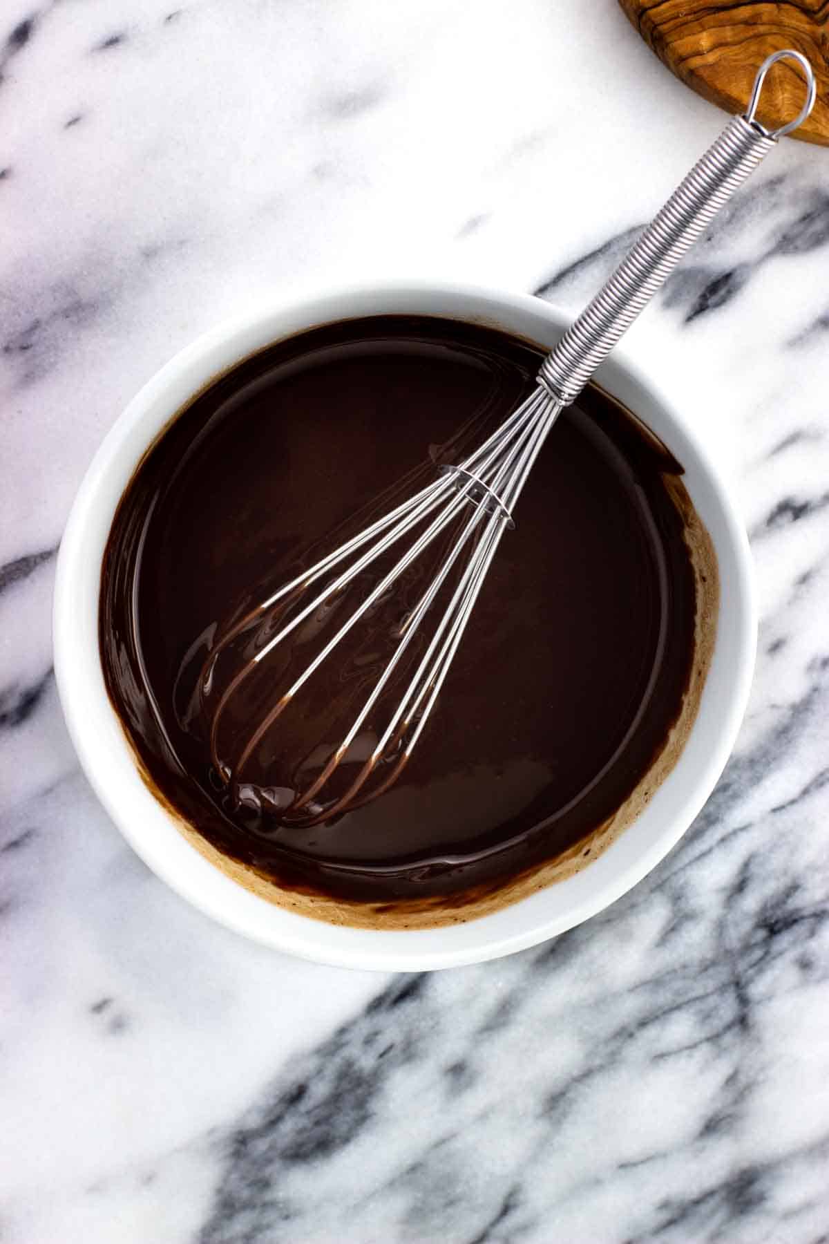 Smooth melted butter and chocolate in a bowl with a whisk.