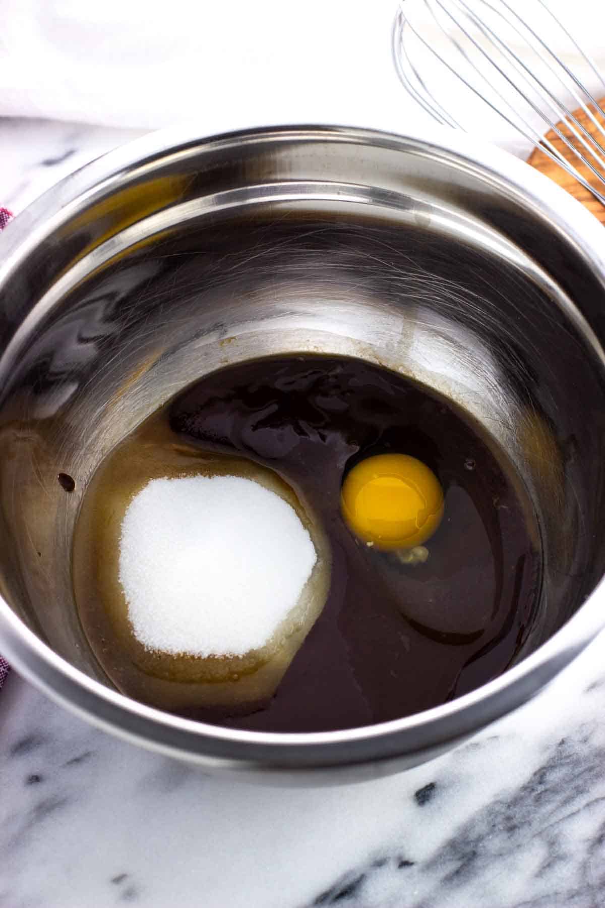 Melted buter/chocolate, sugar, egg, and vanilla in a metal mixing bowl.