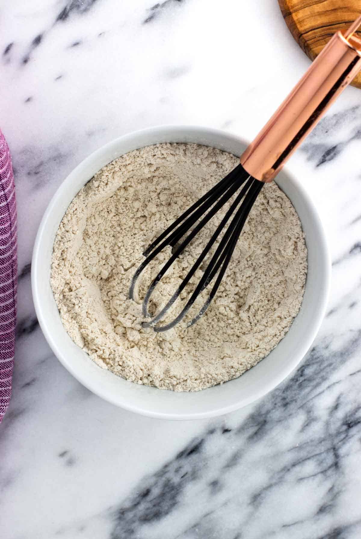 Dry pumpkin layer ingredients in a bowl with a whisk.