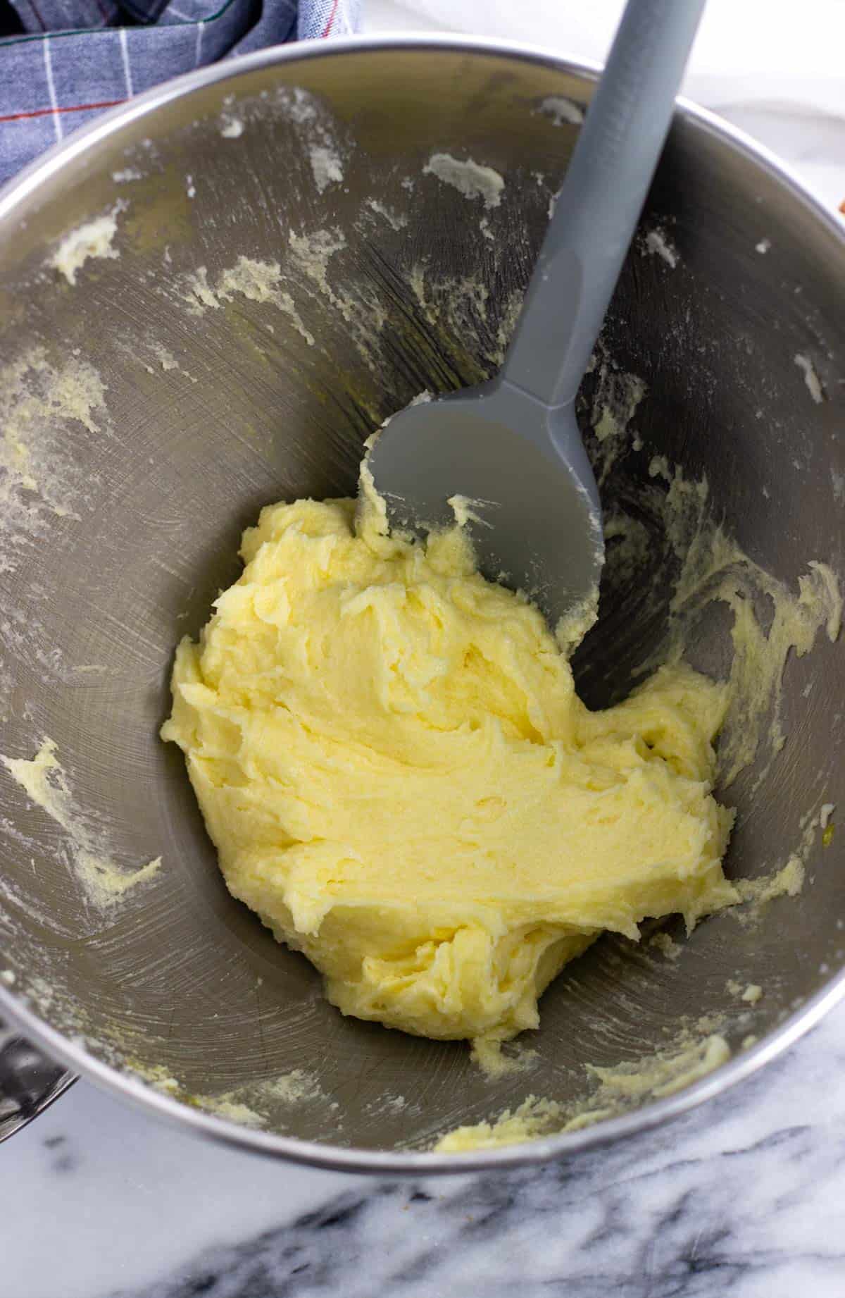 Butter, sugar, and egg mixed together in a bowl with a spatula.