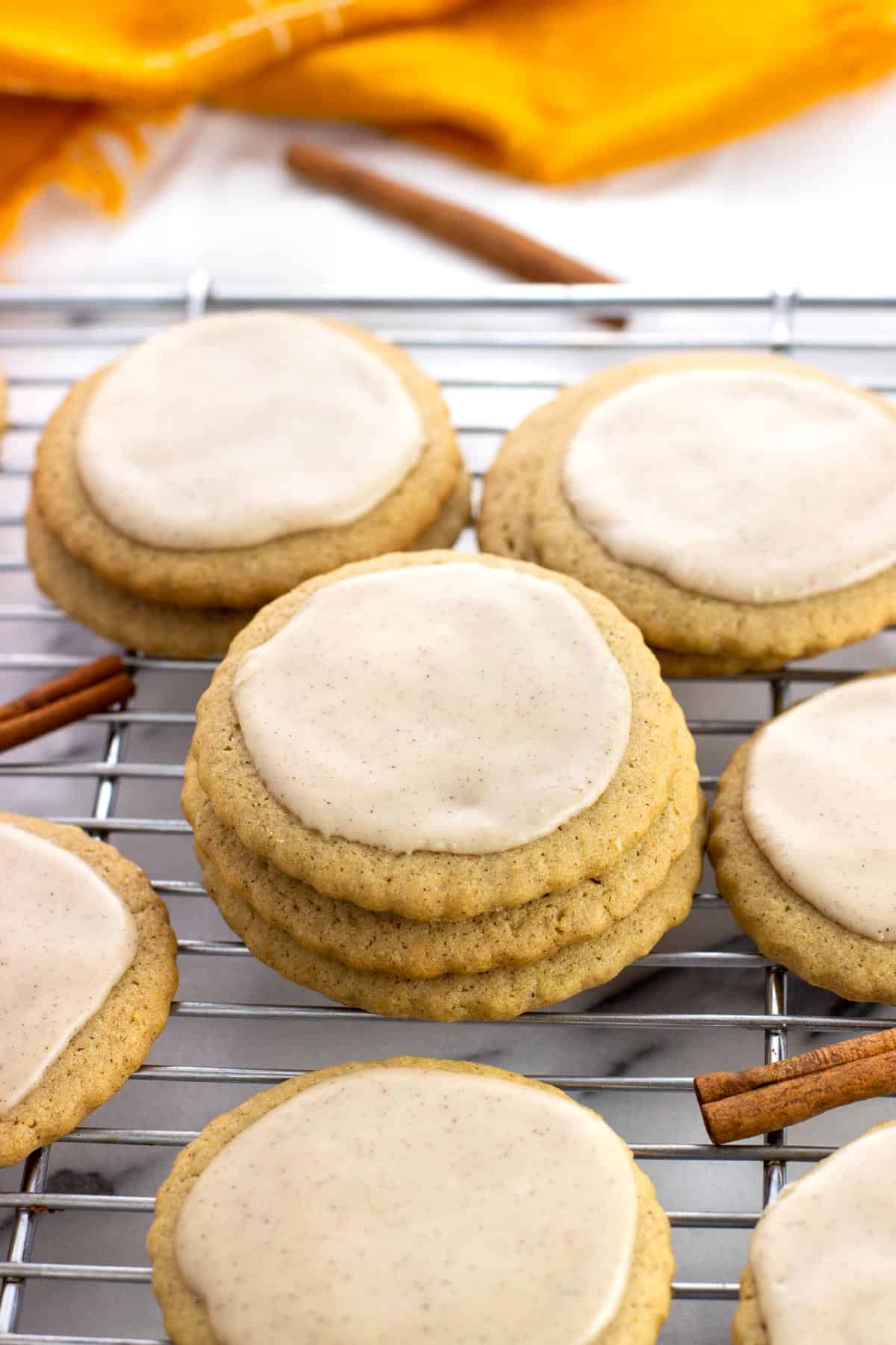 A stack of round iced maple cinnamon sugar cookies on a rack.