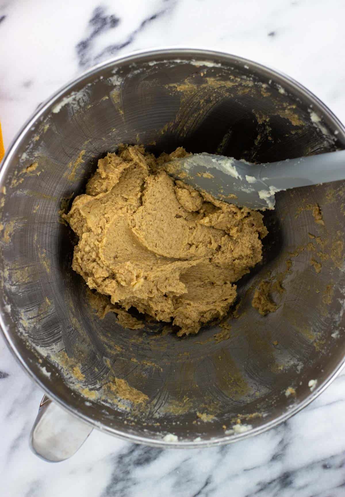 Wet ingredients combined in a mixing bowl with a spatula.