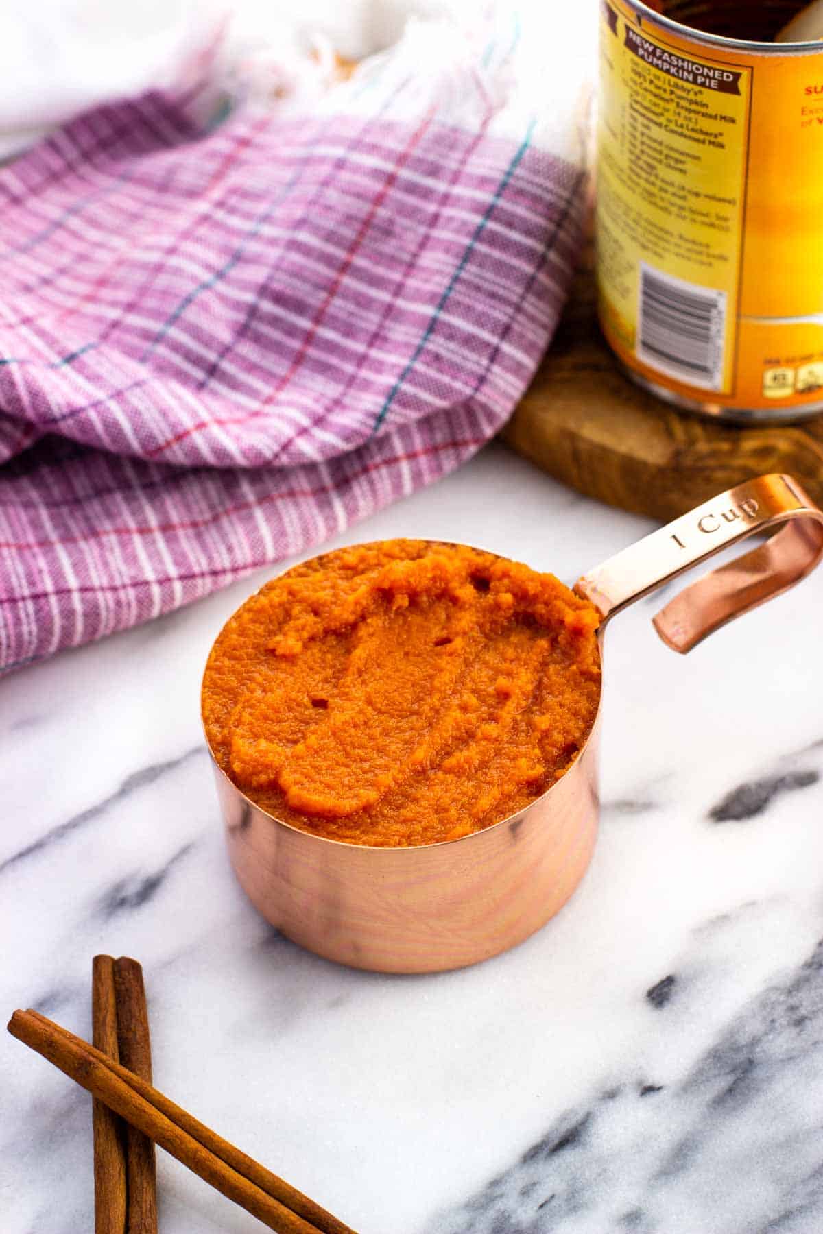 A one-cup measuring cup filled with pumpkin puree.