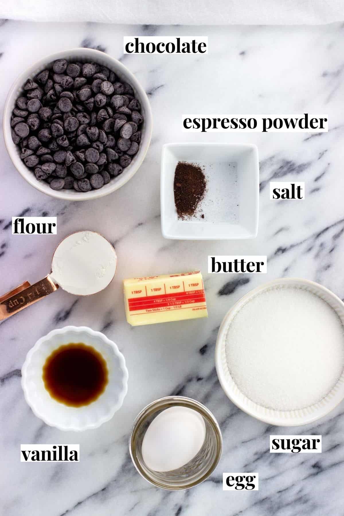 Labeled brownie recipe ingredients on a marble board.