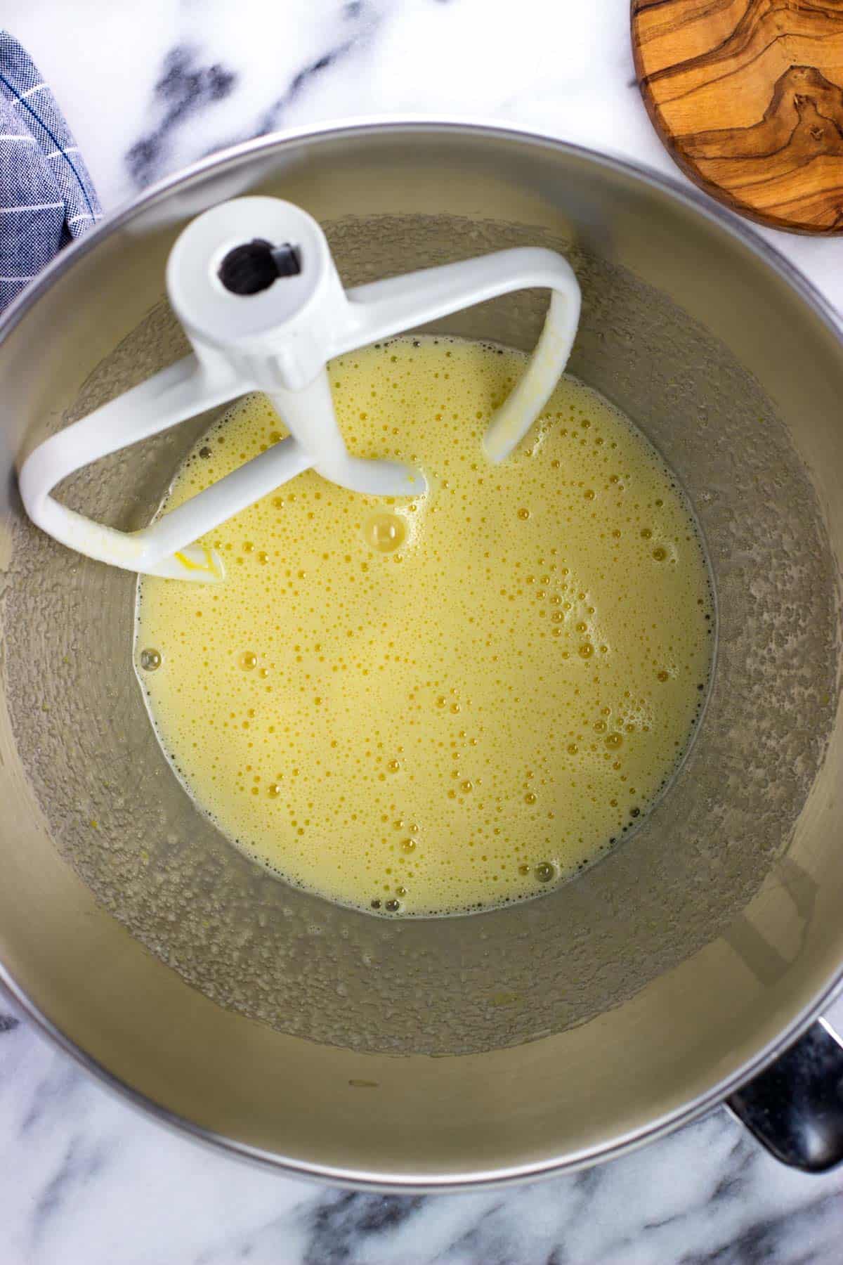 Eggs and sugar mixed together in a metal mixing bowl.