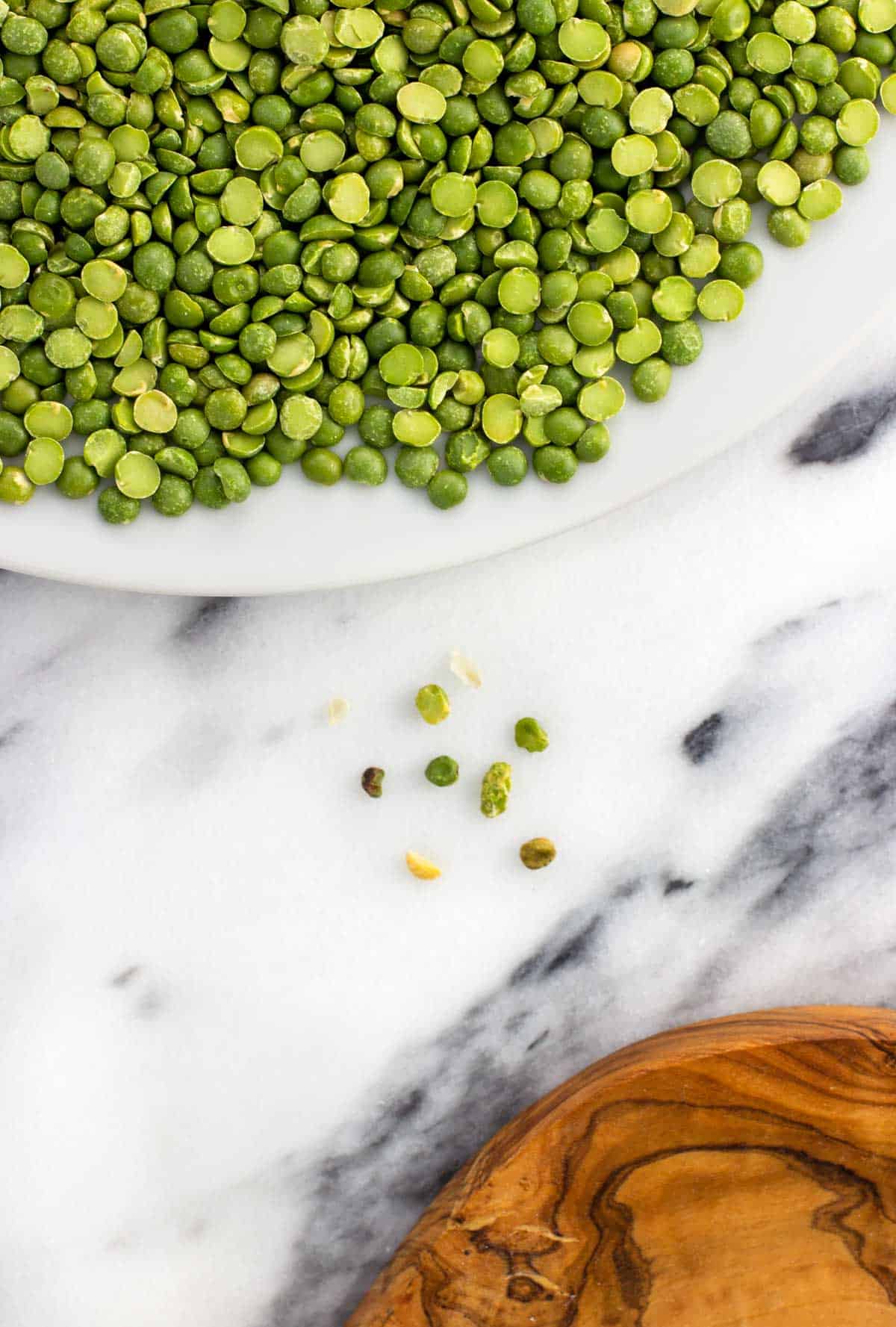 Sorted split pea fragments next to the plate of dried peas.